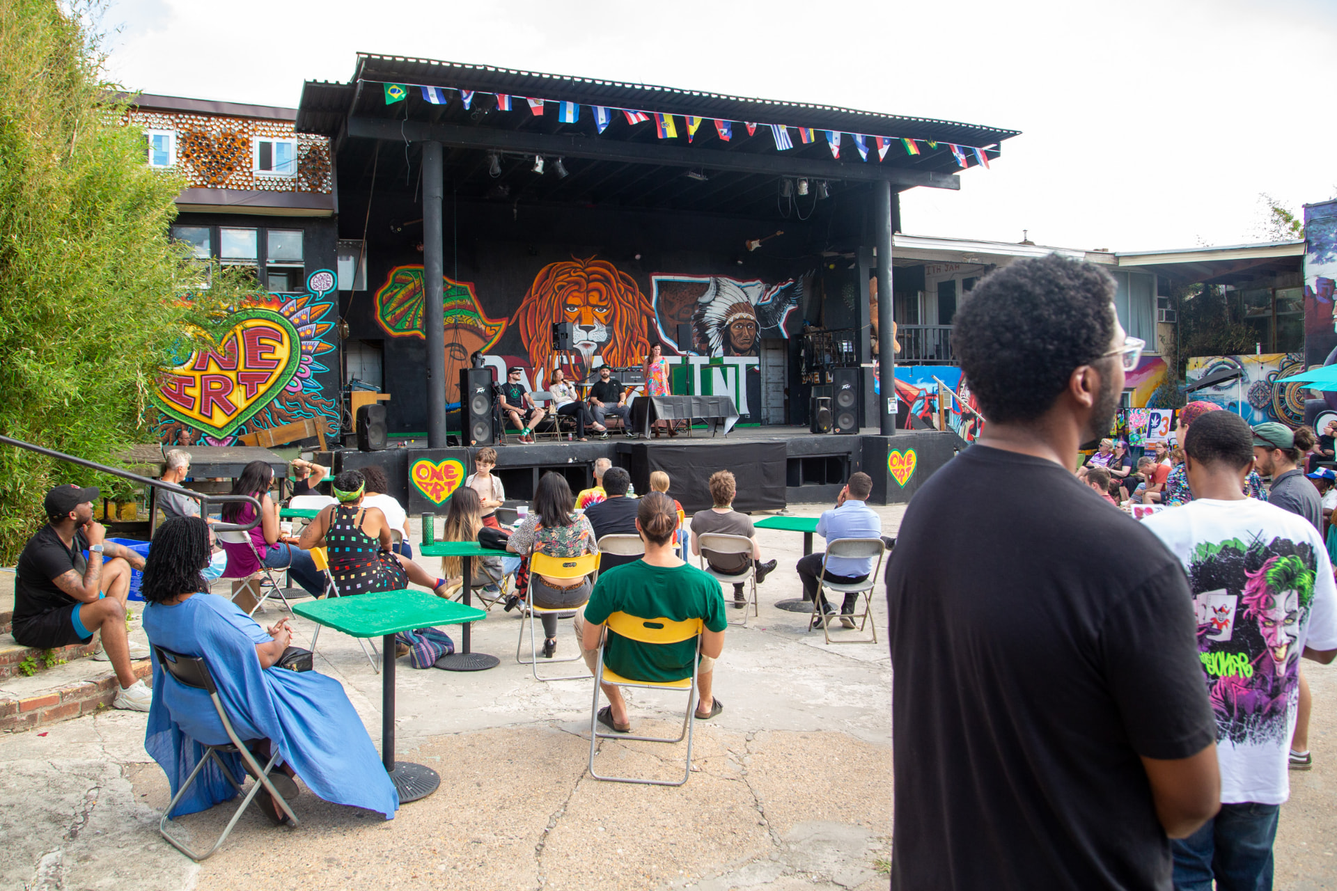 Audience gathered in front of an outdoor stage with colorful murals