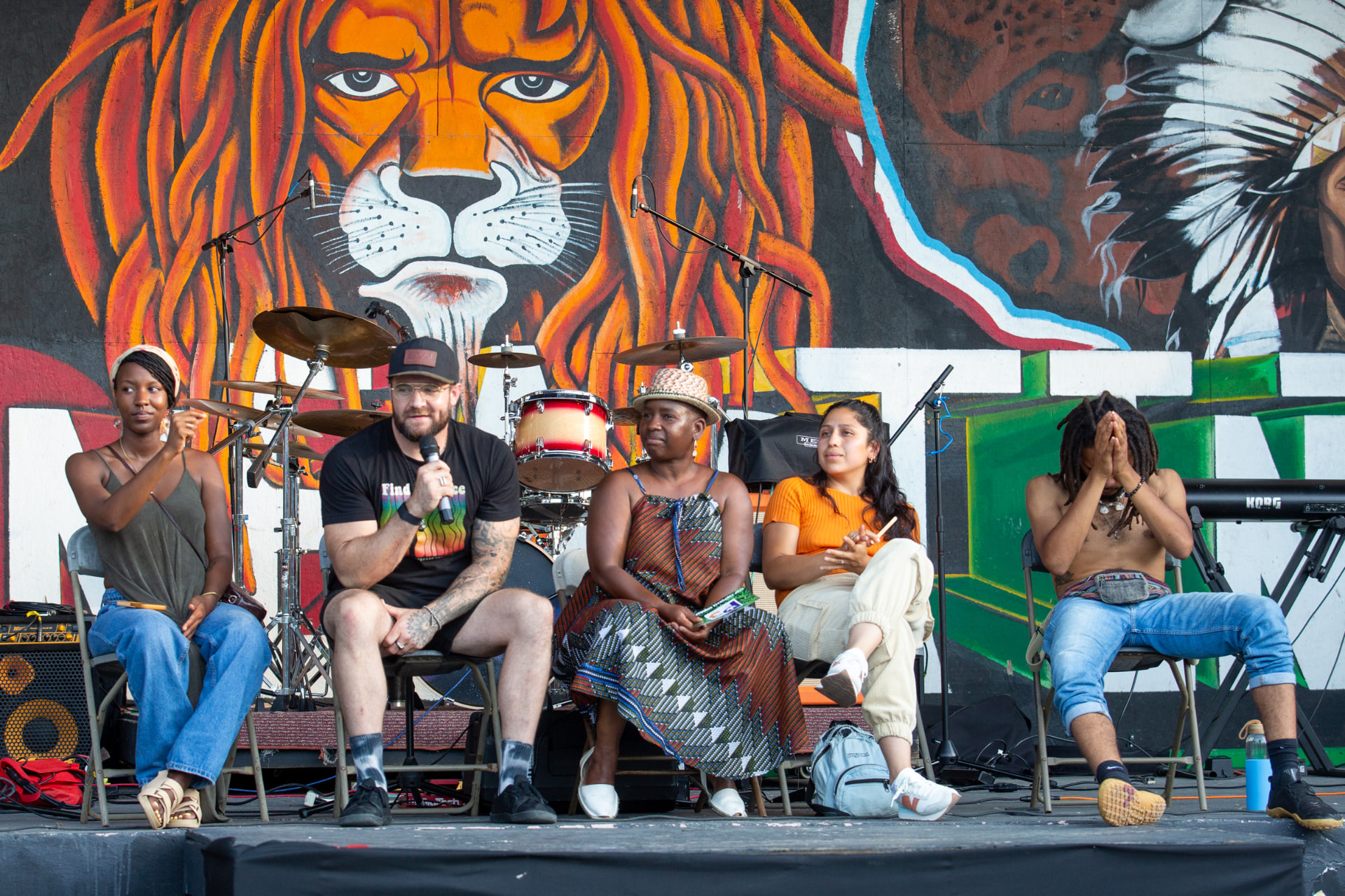 Panel discussion on stage in front of a mural backdrop