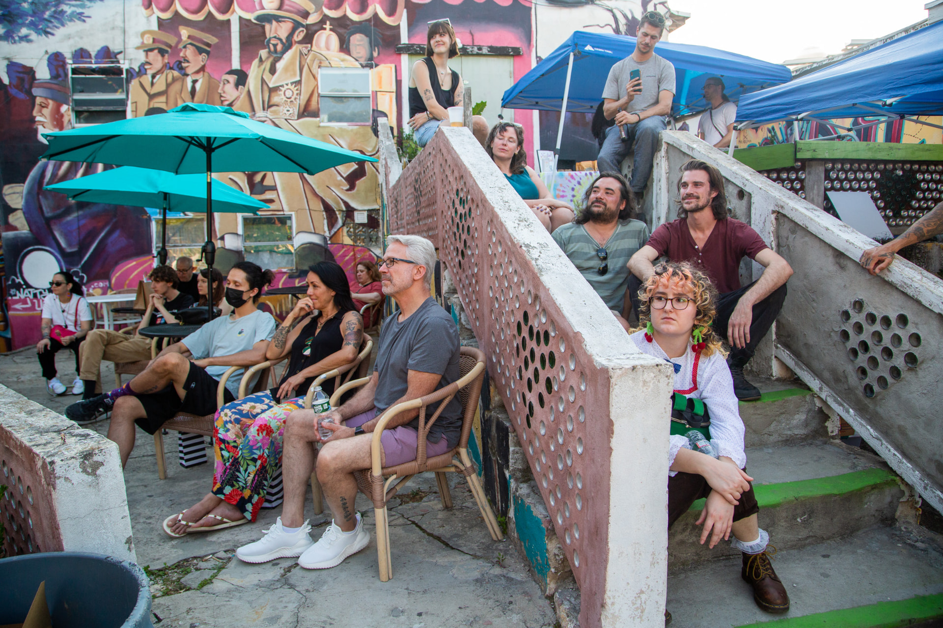 Audience gathered at an outdoor community event with murals