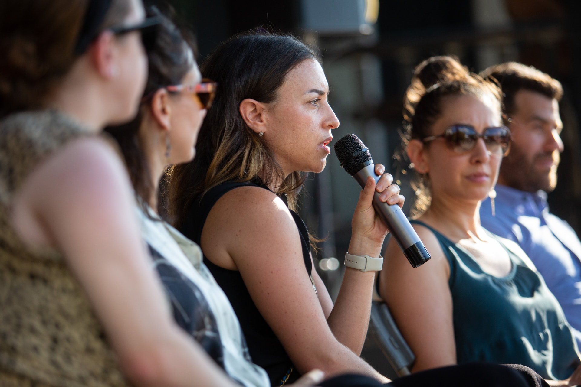 Panelist speaking into a microphone at an outdoor discussion